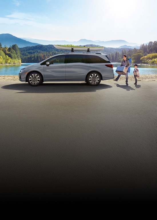 2026 Honda Odyssey Elite in Sonic Gray Pearl profile parked by a lake with a kayak on the roof and people (Minivan).